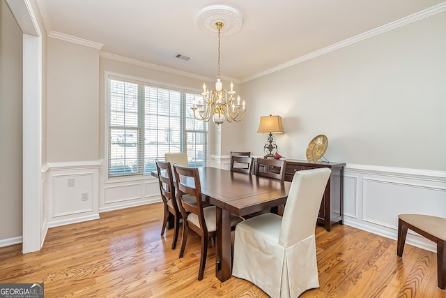 dining area with an inviting chandelier, crown molding, and light hardwood / wood-style flooring