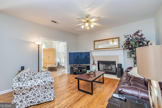 living room featuring a tiled fireplace, hardwood / wood-style floors, and ceiling fan