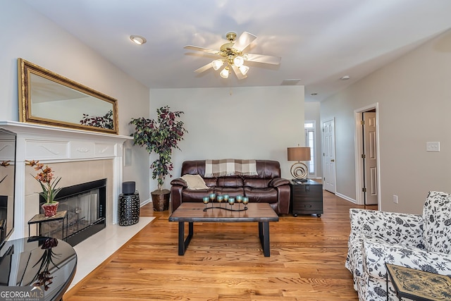 living room featuring ceiling fan, a fireplace, and light hardwood / wood-style floors