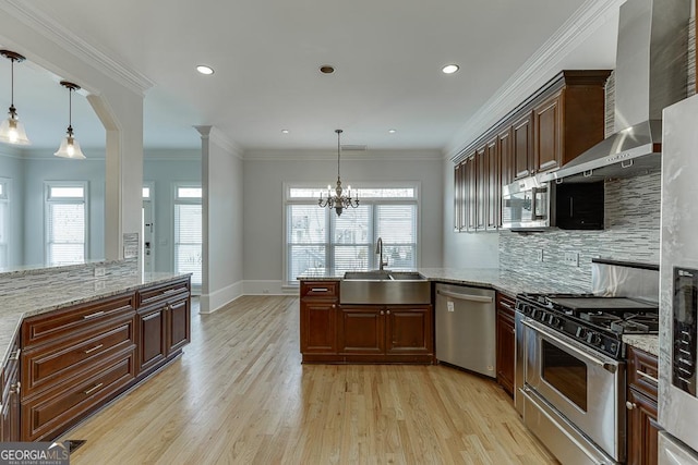 kitchen featuring sink, decorative light fixtures, wall chimney exhaust hood, and appliances with stainless steel finishes