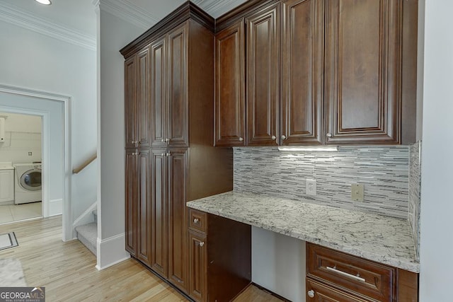 kitchen featuring crown molding, built in desk, decorative backsplash, and light hardwood / wood-style flooring