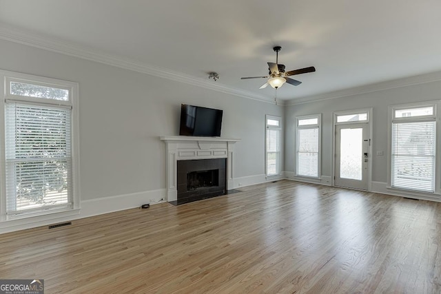 unfurnished living room with crown molding, ceiling fan, a healthy amount of sunlight, and light wood-type flooring