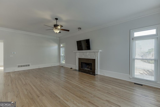 unfurnished living room with a fireplace, ornamental molding, ceiling fan, and light wood-type flooring