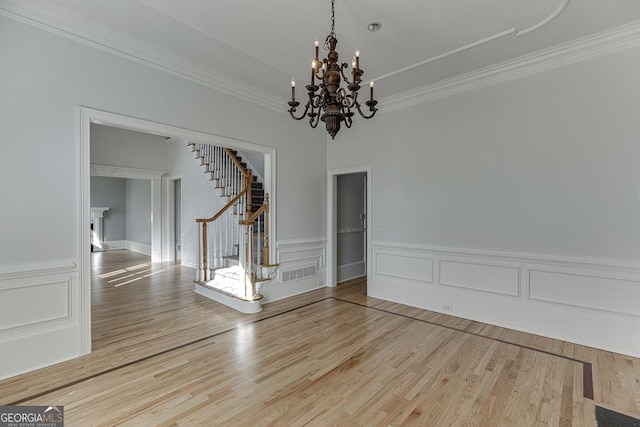 unfurnished dining area featuring crown molding, hardwood / wood-style floors, and a notable chandelier