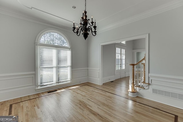 spare room with hardwood / wood-style flooring, crown molding, and a notable chandelier