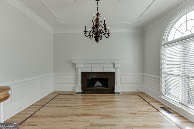 unfurnished living room with a notable chandelier, crown molding, light hardwood / wood-style flooring, and a tile fireplace