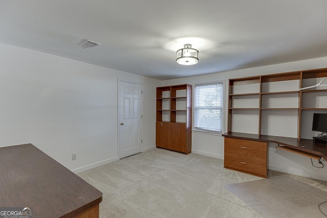 unfurnished office featuring built in desk and light carpet