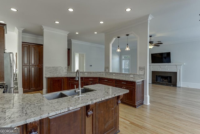 kitchen featuring light stone counters, kitchen peninsula, sink, and stainless steel refrigerator