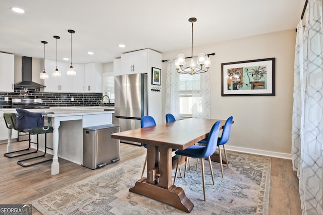 dining room featuring sink, a notable chandelier, and light hardwood / wood-style flooring