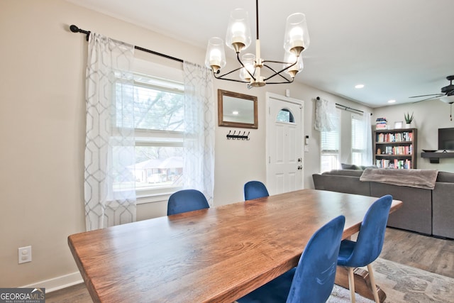 dining room with ceiling fan with notable chandelier and wood-type flooring