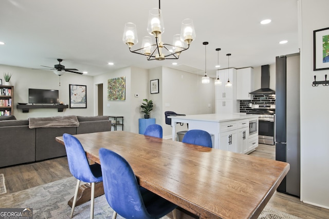 dining room with ceiling fan with notable chandelier and light hardwood / wood-style flooring