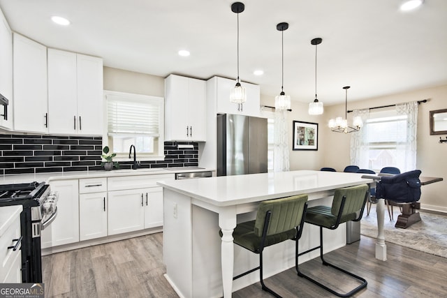 kitchen with pendant lighting, stainless steel appliances, sink, and white cabinets