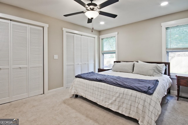 carpeted bedroom with ceiling fan and multiple closets