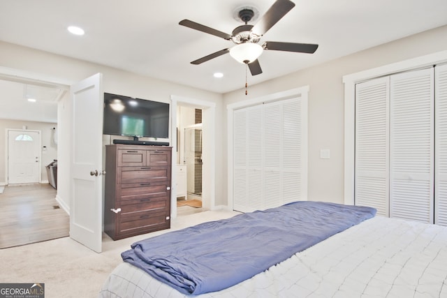 bedroom with multiple closets, light colored carpet, and ceiling fan