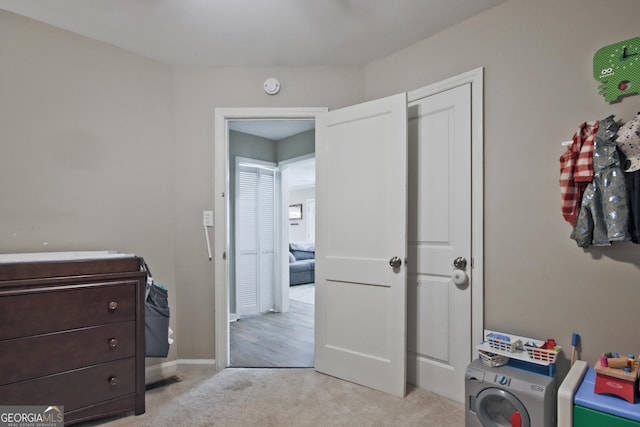 bedroom featuring light carpet and washer / dryer