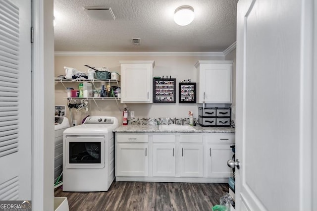 clothes washing area featuring washing machine and clothes dryer, sink, a textured ceiling, ornamental molding, and dark hardwood / wood-style floors