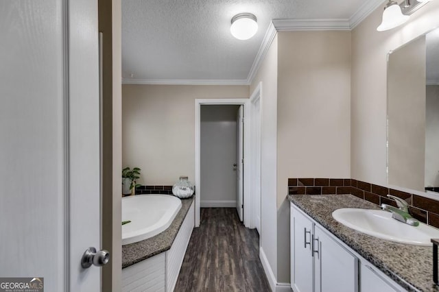 bathroom with crown molding, a textured ceiling, vanity, hardwood / wood-style flooring, and a washtub