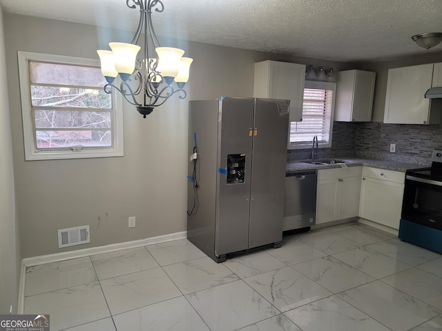 kitchen featuring sink, white cabinets, pendant lighting, stainless steel appliances, and backsplash