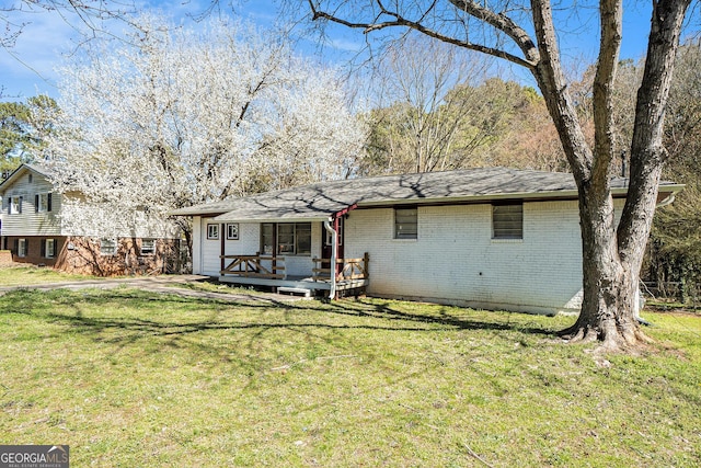 view of front of home featuring a front yard, brick siding, and a wooden deck