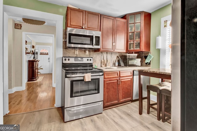 kitchen with tasteful backsplash, stainless steel appliances, and light hardwood / wood-style floors