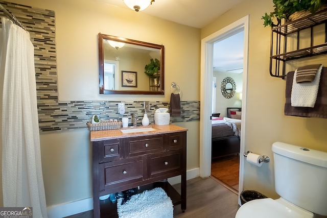 bathroom featuring vanity, wood-type flooring, decorative backsplash, and toilet