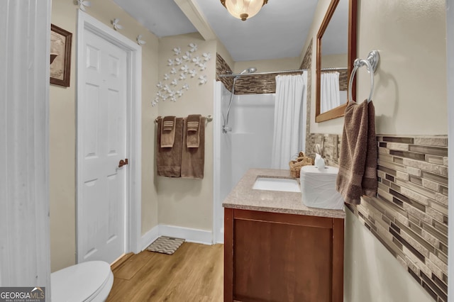 bathroom featuring hardwood / wood-style flooring, vanity, toilet, and curtained shower