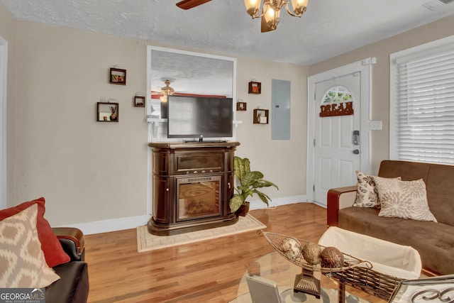 living room with hardwood / wood-style floors, a textured ceiling, electric panel, and ceiling fan