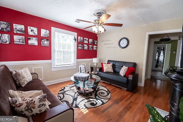 living room featuring ceiling fan, hardwood / wood-style floors, and a textured ceiling