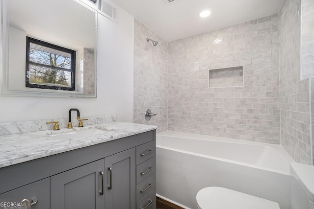 full bathroom featuring vanity, toilet, and tiled shower / bath