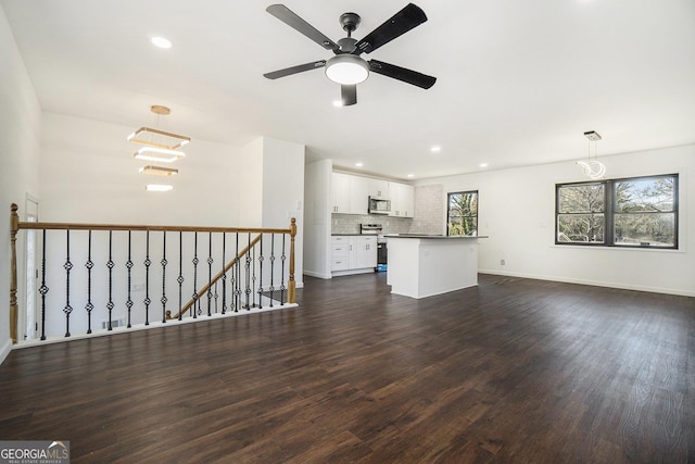 unfurnished living room featuring ceiling fan and dark hardwood / wood-style flooring