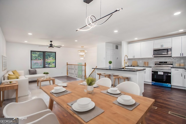 dining area featuring dark wood-type flooring, ceiling fan, and sink