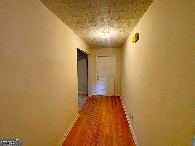 hallway with wood-type flooring and a textured ceiling