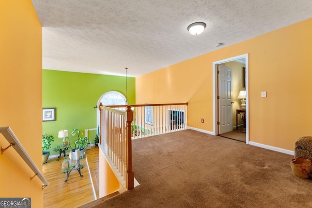 hall with carpet floors and a textured ceiling