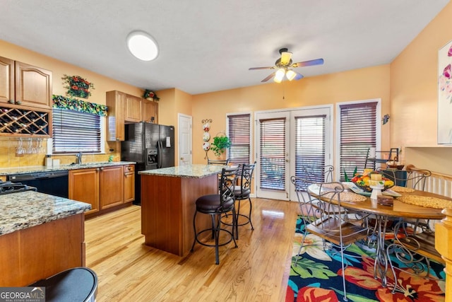 kitchen featuring light stone countertops, light wood-type flooring, a kitchen island, and black appliances