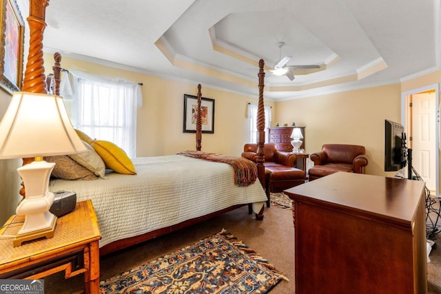 bedroom featuring a raised ceiling, dark colored carpet, crown molding, and ceiling fan