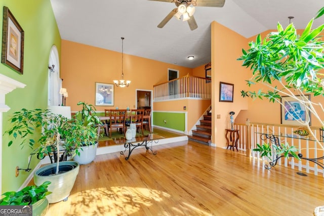 interior space featuring wood-type flooring, ceiling fan with notable chandelier, and high vaulted ceiling