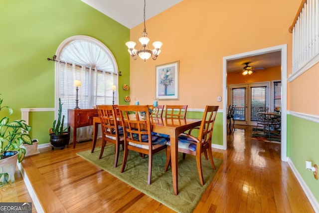 dining space with a notable chandelier, wood-type flooring, and high vaulted ceiling