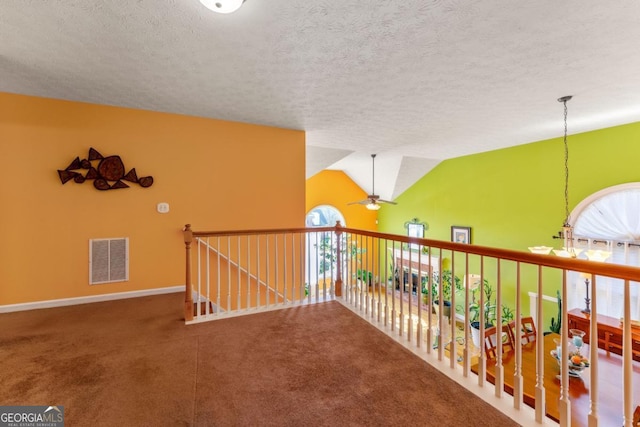 hallway featuring lofted ceiling, carpet, and a textured ceiling