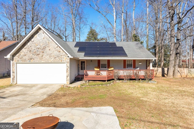 view of front facade with a garage, a wooden deck, a front lawn, and solar panels