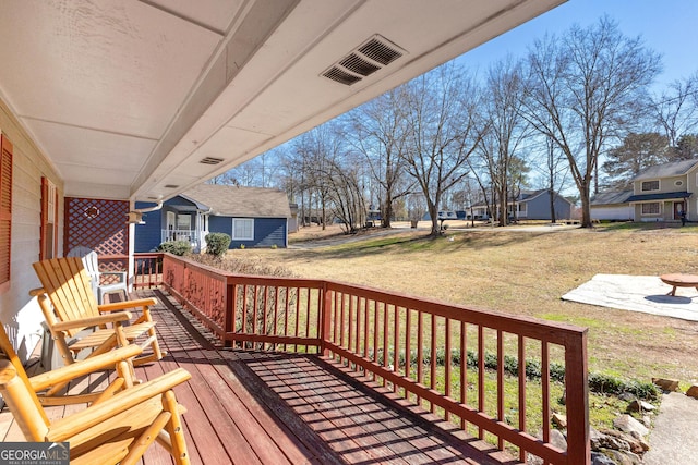 wooden deck featuring a porch and a lawn