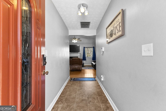 hallway with dark tile patterned flooring and a textured ceiling