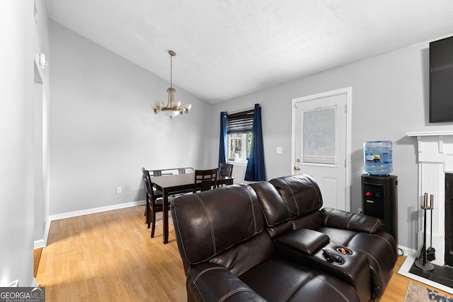 living room with a notable chandelier, wood-type flooring, a textured ceiling, and vaulted ceiling