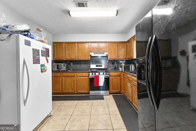 kitchen with stainless steel appliances, light tile patterned floors, a textured ceiling, and decorative backsplash