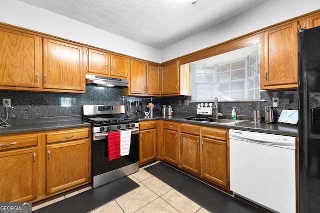 kitchen featuring tasteful backsplash, sink, light tile patterned floors, white dishwasher, and stainless steel gas range