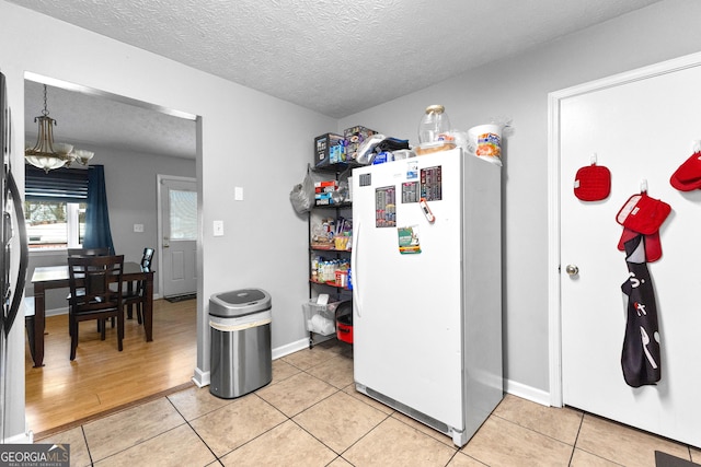 kitchen featuring light tile patterned floors, a chandelier, a textured ceiling, and white refrigerator