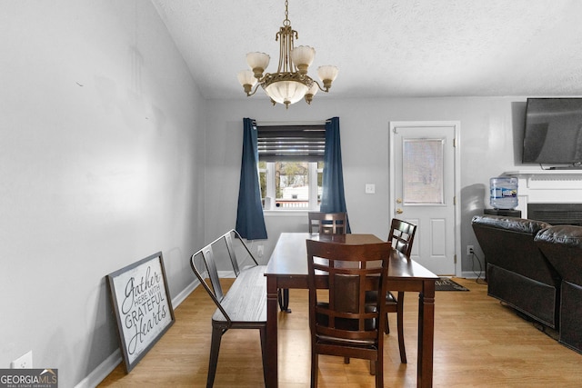 dining room with a chandelier, light hardwood / wood-style floors, and a textured ceiling