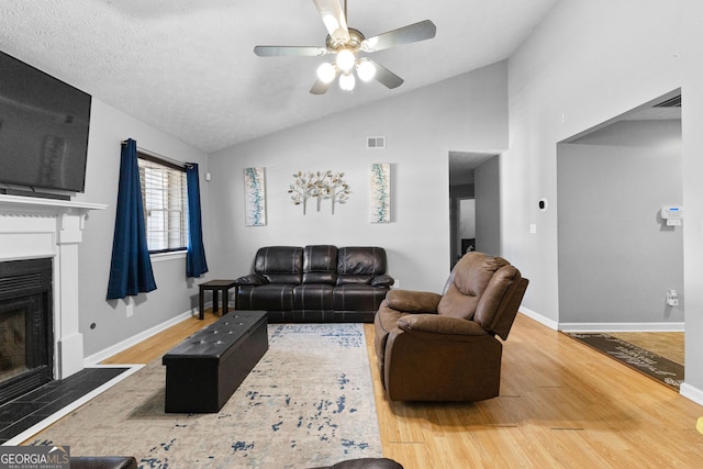 living room with lofted ceiling, hardwood / wood-style floors, a textured ceiling, and ceiling fan