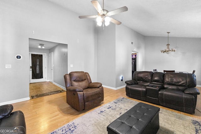 living room featuring hardwood / wood-style flooring, lofted ceiling, and ceiling fan with notable chandelier