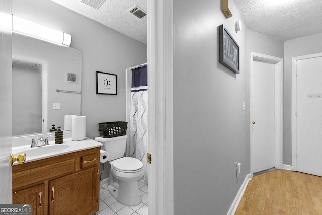 bathroom with hardwood / wood-style flooring, vanity, toilet, and a textured ceiling