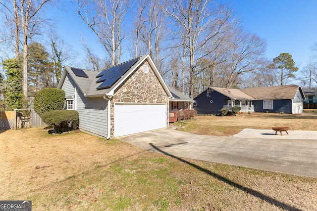 view of property exterior featuring a garage, a lawn, an outdoor fire pit, and solar panels